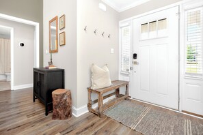 Un couloir avec un banc en bois, une petite armoire et une porte dotée d’une fenêtre.