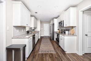 Una cocina moderna con armarios blancos, electrodomésticos de acero inoxidable y piso de madera.
