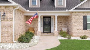 Een huis met twee verdiepingen, een bakstenen gevel, een veranda en een Amerikaanse vlag.