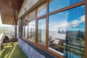 A balcony with a view of a cityscape, a stone wall, and a wooden ceiling. - Alojamientos Turísticos LA APARECIDA (Ampuero)