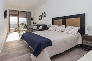 A bedroom with a large bed, a balcony with a table and chairs, and a view of the mountains.