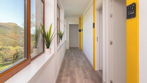 A hallway with a view of a mountainous landscape, potted plants, and doors numbered 109 and 112. - Alojamientos Turísticos LA APARECIDA (Ampuero)