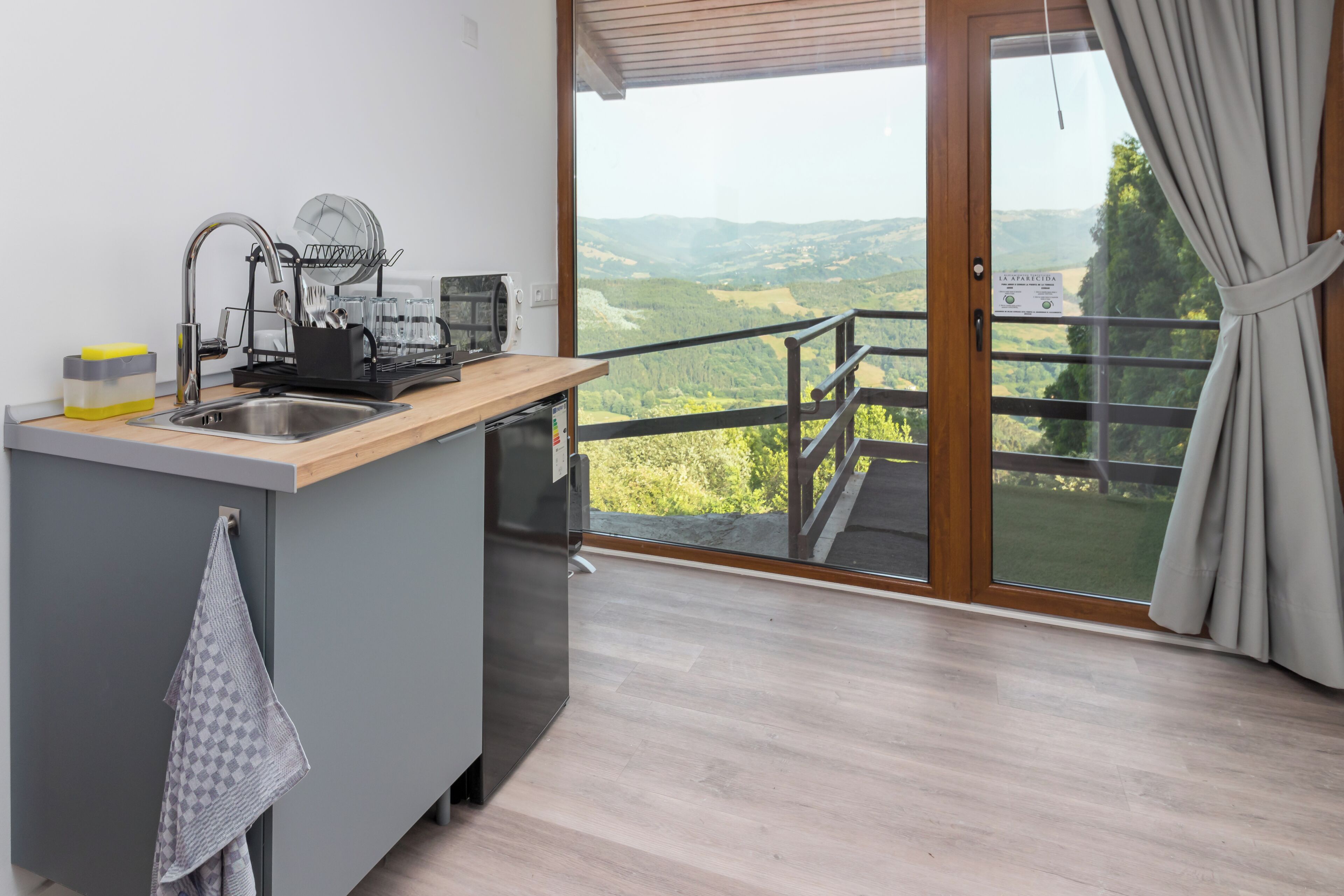 Cocina moderna con pileta, escurreplatos y vista a un paisaje montañoso a través de un amplio ventanal corredero.