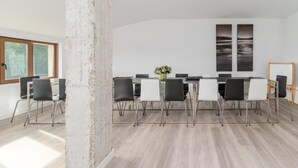 A conference room with a long table, black and white chairs, and two large wall-mounted paintings. - Alojamientos Turísticos LA APARECIDA (Ampuero)