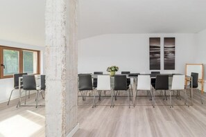 A conference room with a long table, black and white chairs, and two large wall-mounted paintings. - Alojamientos Turísticos LA APARECIDA (AMPUERO)