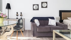 A modern living room with a glass table, a sofa, a lamp, and decorative items on the wall. - Alojamientos Turísticos LA APARECIDA (Ampuero)