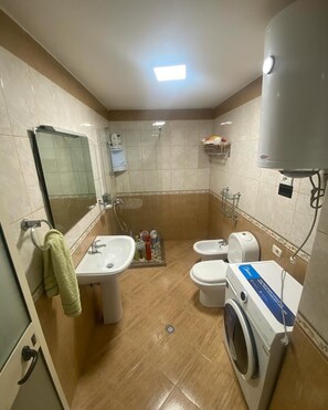 A bathroom with a sink, toilet, bidet, and washing machine. - 2-bedroom apartment in lovely Golem with AC and comfort (Golem)