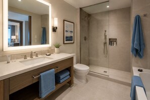 A modern bathroom with a large mirror, dual sinks, a toilet, a shower area, and a bathtub. - The Avelyn Suites (Toronto)