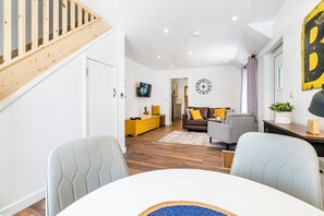 A modern living room with a staircase, a sofa, a coffee table, and a TV. - Unique Devon Cottages - Sunrise Cottage - Stylish & Comfortable (Exmouth)