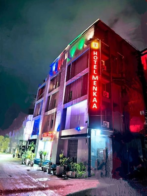 Et hotel med flere etager og et markant neontegn på facaden.