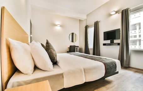 Une chambre d’hôtel moderne dotée d’un grand lit, d’un téléviseur à écran plat, d’une table de chevet et d’une fenêtre avec des rideaux.. Hotel Menkaa