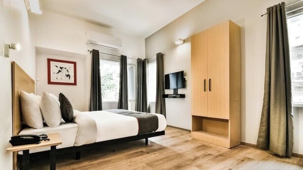 A modern bedroom with a bed, a desk, a wardrobe, and a TV. - Hotel Menkaa (Patna)