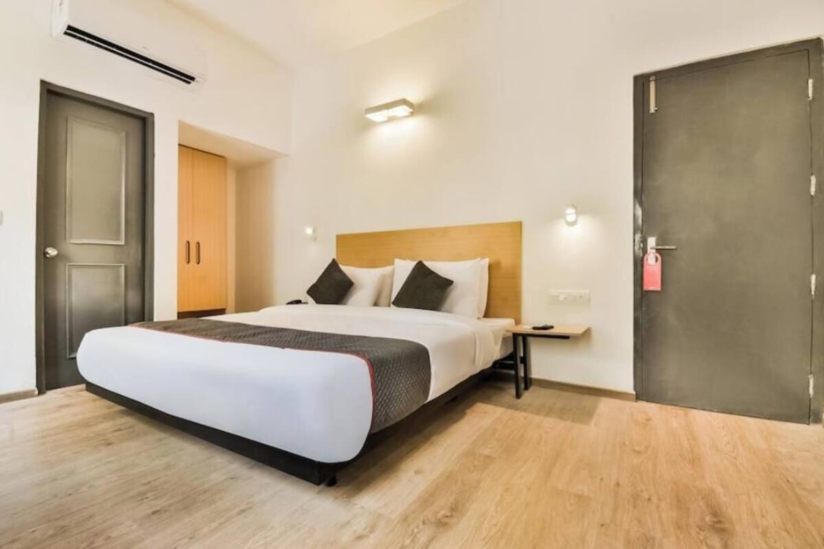 Una habitación de hotel con cama, mesita de noche y puerta.