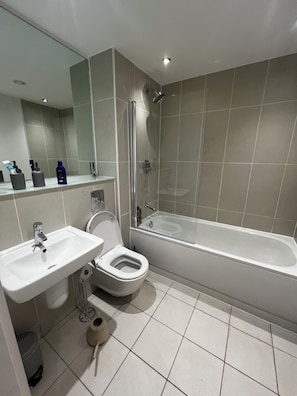 Et moderne badeværelse med vask, toilet og badekar.