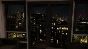 Una sala de estar moderna con ventanas amplias, un sofá oscuro y piso de madera.