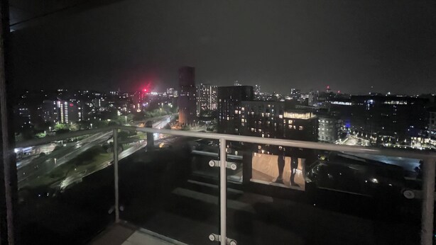A nighttime cityscape viewed from a balcony with a glass railing. - High-Rise 2BR | Balcony & City Views | Sleeps 8 (Leeds)