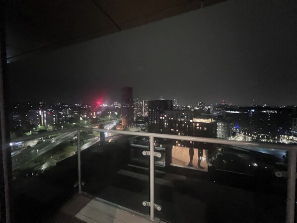 A nighttime cityscape viewed from a balcony with a glass railing. - High-Rise 2BR | Balcony & City Views | Sleeps 8 (Leeds)