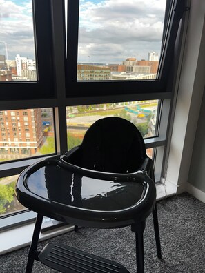 A black office chair in front of a large window with a city view. - High-Rise 2BR | Balcony & City Views | Sleeps 8 (Leeds)