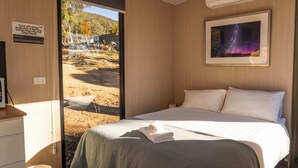 Ein Schlafzimmer mit einem Bett, einem gerahmten Bild, einem Schild und Blick auf einen Außenbereich.