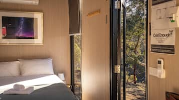 Quarto de hotel com uma cama, uma imagem emoldurada de uma galáxia, uma janela e uma porta que dá para o exterior.