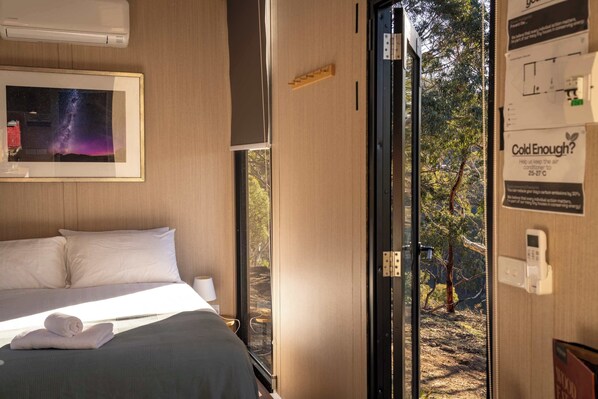 A hotel room with a bed, a framed picture of a galaxy, a window, and a door leading outside.