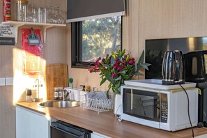 Une cuisine équipée d’un four à micro-ondes, d’une bouilloire et d’un évier.