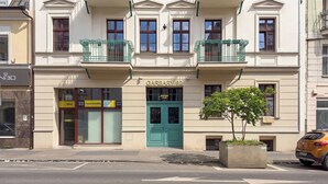 A building with a green door labeled 'GARBARY 62,' a small tree in a planter, and a yellow sign with 'Idfast' and 'Powabimally KRP' text. - Stylish Studio with a Mezzanine | Near the Market Square (Poznań)