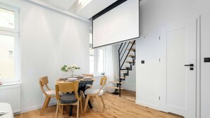 A modern room with a dining table, chairs, a staircase, and a white door. - Stylish Studio with a Mezzanine | Near the Market Square (Poznań)