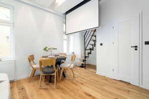 Ein modernes Zimmer mit Esstisch, Stühlen, einer Treppe und einer weißen Tür.