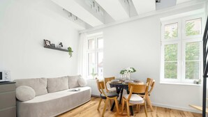 A modern living room with a sofa, dining table, chairs, and a window with a view. - Stylish Studio with a Mezzanine | Near the Market Square (Poznań)