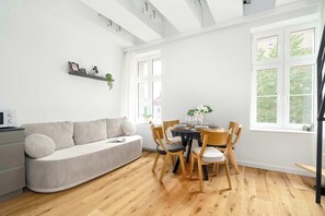 Ein modernes Wohnzimmer mit einer Couch, einem Esstisch, Stühlen und einem Fenster mit Blick.