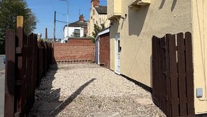A narrow alleyway with a gravel path leading to a building with a brown gate. - Central Hull, 3Br Contractors & Street Parking (Hull)