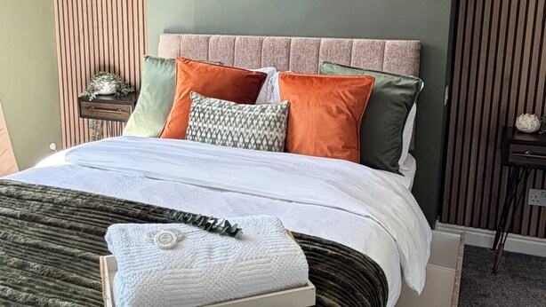 A neatly made bed with a variety of pillows and a folded towel on a dark green bedspread. - Central Hull, 3Br Contractors & Street Parking (Hull)
