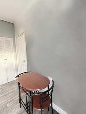 A dining area with a round table and chairs, a white door, and a grey wall.