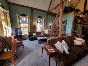 A cozy living room with a brown sofa, wooden chairs, a coffee table, and a Christmas tree. - The Barn Inn Bed and Breakfast (Millersburg)
