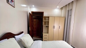 A bedroom with a bed, a wardrobe, a door, and a ceiling light. - Adorable 2-bedroom bed & breakfast in vibrant Kigali (Kigali)