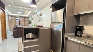 A modern kitchen with a built-in refrigerator, a coffee maker, and a dining area with a table and chairs. - Adorable 2-bedroom bed & breakfast in vibrant Kigali (Kigali)