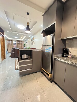 Uma cozinha moderna com geladeira embutida, cafeteira e área de jantar com mesa e cadeiras.