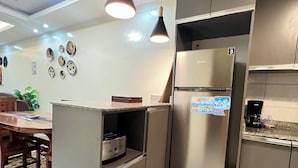 A modern kitchen with a built-in refrigerator, a coffee machine, and a dining area with a table and chairs. - Adorable 2-bedroom bed & breakfast in vibrant Kigali (Kigali)