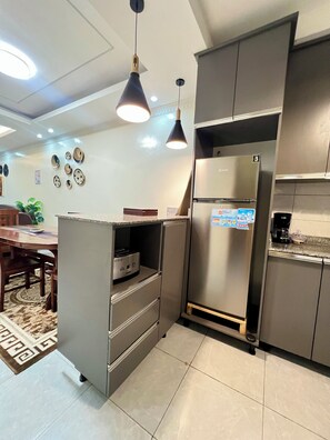 Uma cozinha moderna com frigorífico embutido, máquina de café e área de jantar com mesa e cadeiras.