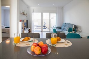 Uma área de refeições com uma mesa posta para o café da manhã, incluindo croissants, maçãs e suco de laranja.