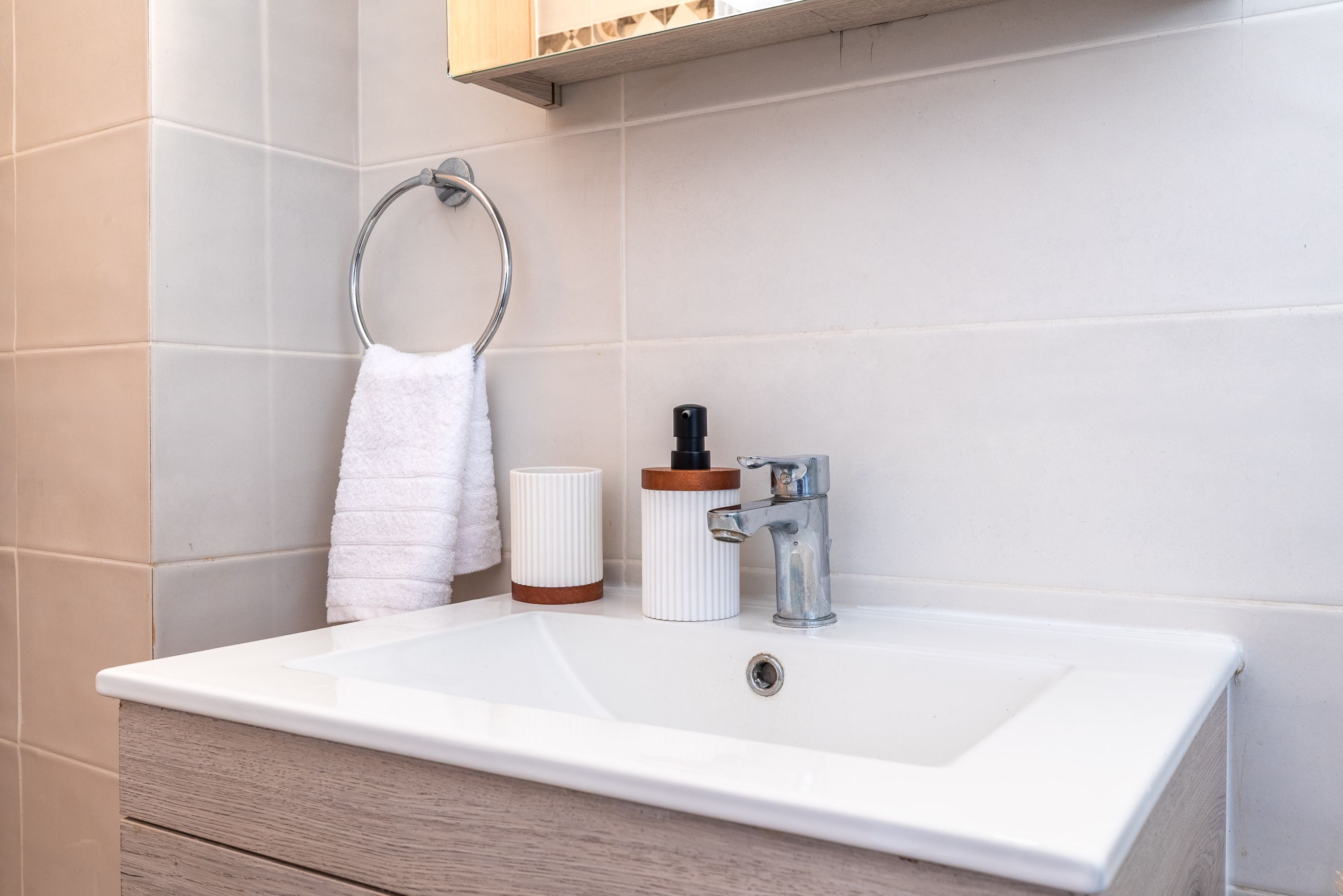 A bathroom with a white sink, a towel ring, and a soap dispenser.