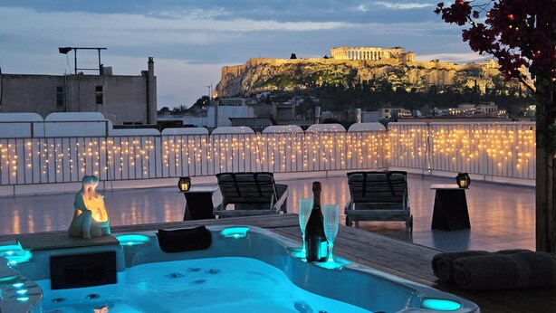 A rooftop terrace with a hot tub, lounge chairs, and a view of a historic building. - Acropolis View Apartment in Heart of Monastiraki (Athina)