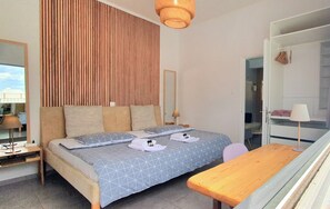 Een slaapkamer met een bed, nachtkastje, lamp en een kledingkast.