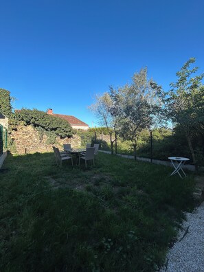 Ein Garten mit einer Steinmauer, einem Tisch und Stühlen.