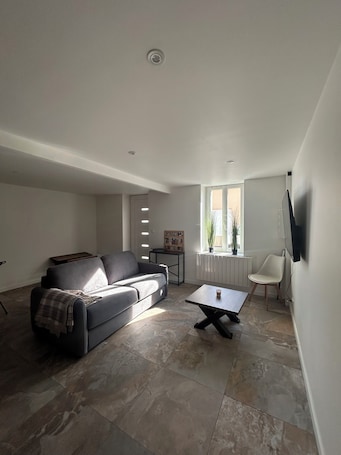 A modern living room with a sofa, a coffee table, a TV, and a window with a view.. La Petite Maison