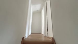 Passadís estret i ben il·luminat amb escales de fusta que condueixen a una porta.
