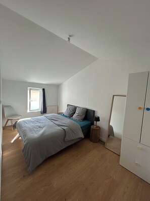 Ein Schlafzimmer mit einem Bett, einem Stuhl, einem Kleiderschrank und einem Fenster.