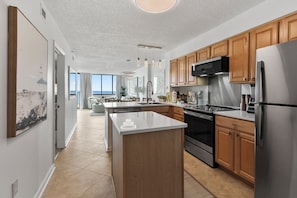 A modern kitchen with wooden cabinets, stainless steel appliances, and a large island. - Spinnaker #304 - Beautiful Oceanfront Condo in North Myrtle Beach (North Myrtle Beach)