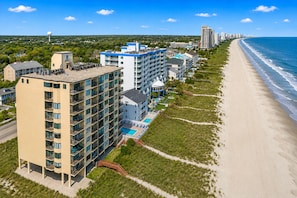A coastal hotel with multiple floors, a swimming pool, and a beach view. - Spinnaker #304 - Beautiful Oceanfront Condo in North Myrtle Beach (North Myrtle Beach)
